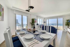 a dining room with a white table with a view of the ocean at Apartamento Capri - PlusHolidays in Calpe