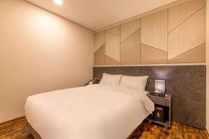 a bedroom with a white bed and a wall at Urban-Est Hotel in Goyang