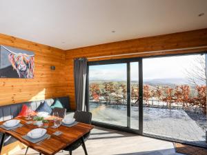 a dining room with a table and a large window at Hilltop Lodge in Corwen