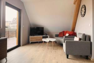 a living room with a couch and a tv and a table at La Goguette - Charmant gîte chez le vigneron in Dorlisheim