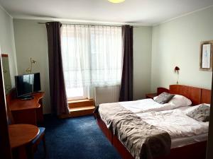 a hotel room with a bed and a television at Hotel Dowhań in Nowe