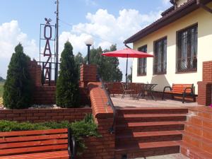 a patio with a red umbrella next to a building at Bar Oaza in Szczerców