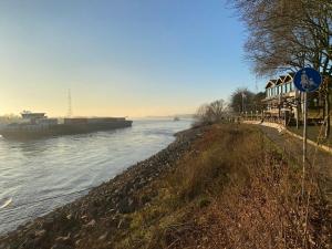 a river with a boat in the water at Wohnen direkt an der Rheinpromenade mit Whirlpool und Sauna in Götterswickerhamm