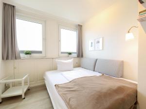 1 dormitorio pequeño con 1 cama y 2 ventanas en Appartement Kaya, en Westerland
