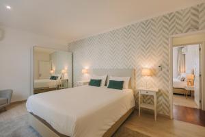 a bedroom with a large white bed and a mirror at Beach House by Azores Villas in São Roque