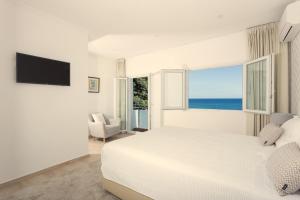 ein weißes Schlafzimmer mit einem großen Bett und einem Fenster in der Unterkunft Beach House by Azores Villas in São Roque