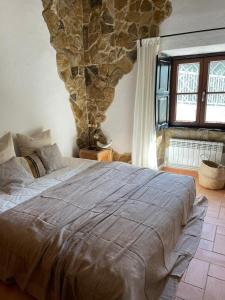 1 dormitorio con 1 cama grande y pared de piedra en Adamah Vayu -Casa Serenida, en Loulé