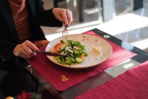 une personne mangeant une assiette de nourriture sur une table dans l'établissement Spa Hotel Grace Forum, à Erevan