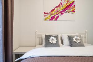 Un dormitorio con una cama con almohadas y una pintura en Wola Glamour Apartment, en Varsovia