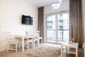 un comedor blanco con mesa y ventana en Wola Glamour Apartment, en Varsovia