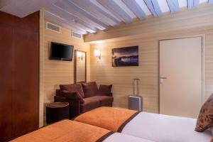 1 dormitorio con 1 cama, 1 silla y TV en Hotel Saint Honore 85 en París