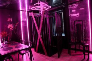 Pokój z fioletowymi światłami, stołem i osobą w obiekcie BDSM Apartament Luxxx gorące serce Częstochowy - ADULTS ONLY w mieście Częstochowa