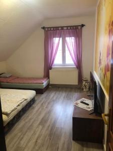 a room with two beds and a window with purple curtains at Edit Vendégház Balatonszentgyörgy in Balatonszentgyörgy