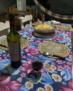 a table with a bottle of wine and a glass at Pousadinha da Lulu - Pontal Mangue Seco in Indiaroba