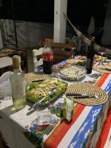 una mesa con platos de comida y una botella de refresco en Pousadinha da Lulu - Pontal Mangue Seco, en Indiaroba