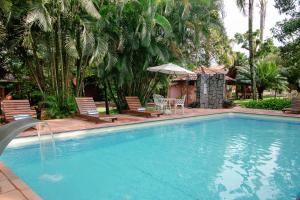 a large swimming pool with chairs and an umbrella at Pouse no Jardim in Pirenópolis