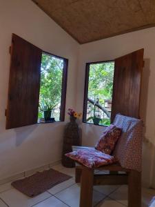 a living room with a chair and two windows at Pousada Casa Mágica -Taipu de Fora in Barra Grande