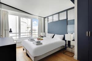 a bedroom with a large white bed and large windows at Amazing apartments - Arc de Triomphe-Champs Elysée in Paris