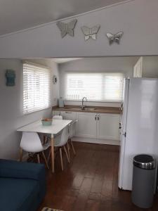 a kitchen with a table and a white refrigerator at Holiday Chalet at Gwithian Sands in Cornwall in Gwithian