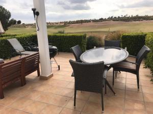 un patio con mesa y sillas y vistas a un campo de golf en Condado de Alhama PH1502, en Alhama de Murcia