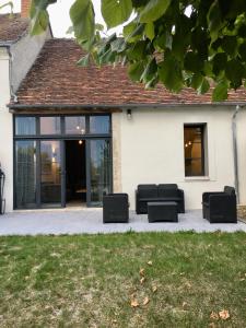 een patio met zwart meubilair voor een huis bij Les gîtes du Val de Chambord in Huisseau-sur-Cosson