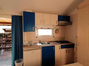 a small kitchen with blue cabinets and a sink at Tobacco Road camping Sirolo in Sirolo