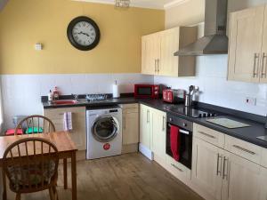 a kitchen with a washing machine and a clock on the wall at Whitegate in Llandudno