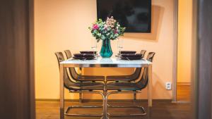 a table with chairs and a vase of flowers on it at Central Ruterra 3 BDR Apartment in Prague