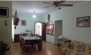 ein Wohnzimmer mit einem Tisch und einem Deckenventilator in der Unterkunft Casa 200m da praia 3 dorm. p/ 12 pessoas in Peruíbe