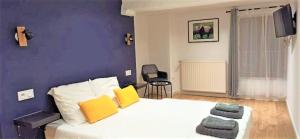 una camera da letto con un grande letto bianco con cuscini gialli di L'auberge aux volets rouges à 4 min du Zoo de Beauval 2-10 pers a Saint-Aignan