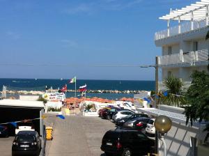 a parking lot with cars parked next to the ocean at Residence Fanny in Rimini