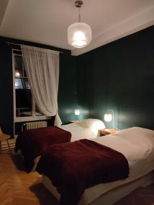 a bedroom with two beds and a green wall at Clos Terre-lune in Nuits-Saint-Georges