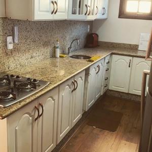 a kitchen with white cabinets and a stove top oven at Meu cantinho na Serra- 5 Minutos de Itaipava in Petrópolis +7 photos