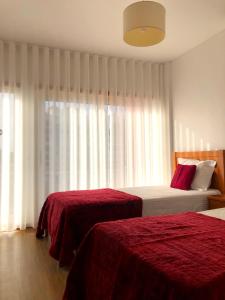 サン・マルティーニョ・ド・ポルトにあるAlojamentos Campo & Mar - T1 com Piscinaのベッドルーム1室(赤いシーツと窓付)