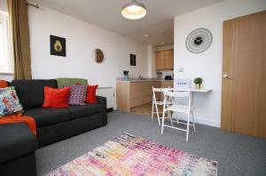 a living room with a black couch and a kitchen at Penners Place by Tŷ SA in Newport