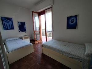 sypialnia z 2 łóżkami i drzwiami na balkon w obiekcie La Casa Bianca - Alghero Calich w mieście Alghero