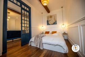 Schlafzimmer mit einem Bett mit weißer Bettwäsche und orangefarbenen Kissen in der Unterkunft L'Haussmann, Rare, Appartement Vue Château et Palmiers in Pau