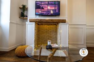 ein Wohnzimmer mit einem Kamin und einem TV darüber. in der Unterkunft L'Haussmann, Rare, Appartement Vue Château et Palmiers in Pau