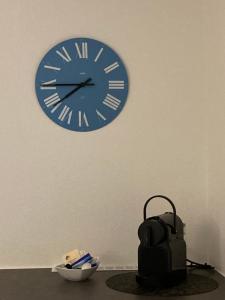 une horloge bleue suspendue sur un mur à côté d'un bol dans l'établissement Furnished studio with garden Seefeld I Tiefenbrunnen, à Zurich