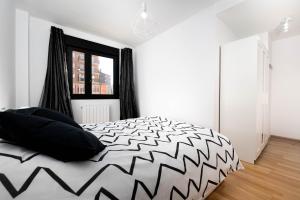 a bedroom with a black and white bed and a window at Apartamento en Sabiñánigo con amplia y soleada terraza in Sabiñánigo