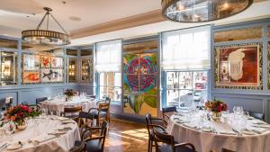 a restaurant with white tables and chairs and windows at En-suite luxury large bedroom with parking and two tickets to Kew Gardens in Kew Gardens