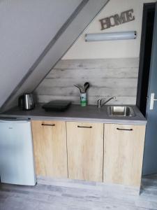 a kitchen under the stairs with a sink and a refrigerator at CHAMBRE STUDIO avec KICHENETTE SOLEIL DE NACRE in Hermanville-sur-Mer