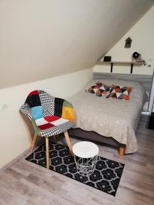 a bed and a chair in a room at CHAMBRE STUDIO avec KICHENETTE SOLEIL DE NACRE in Hermanville-sur-Mer