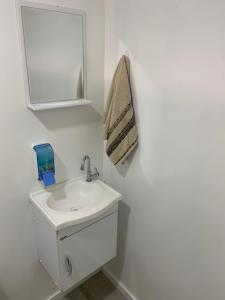 a white bathroom with a sink and a mirror at Chalé Casal Perto Praia LAGOINHA - Wi-Fi e Ar-Condicionado - Vila Santa Barbara in Ubatuba