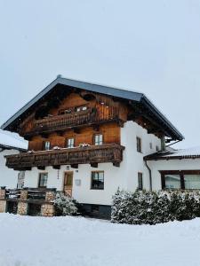 a large wooden house with a balcony in the snow at Ferienhaus Anna in Zell am Ziller