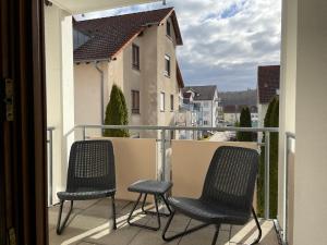 two chairs on a balcony with a view of a building at Modernes Apartment I Parkplatz I Netflix I Zentrum in Renningen