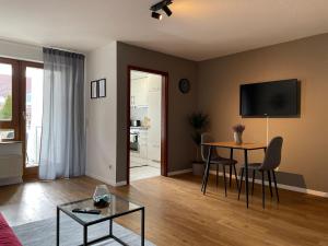 a living room with a table and a tv at Modernes Apartment I Parkplatz I Netflix I Zentrum in Renningen