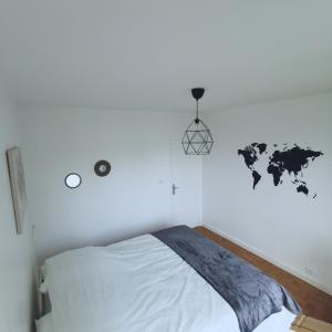 a white bedroom with a bed and a world map on the wall at Chambre Monde Tout confort Saint-Marceau in Orléans