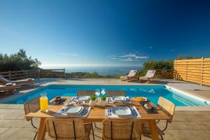 a wooden table with chairs next to a swimming pool at Villa Freya - Melisou Villas in Kalamitsi