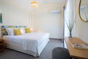 a white bedroom with a bed and a table at Villa Freya - Melisou Villas in Kalamitsi +30 photos